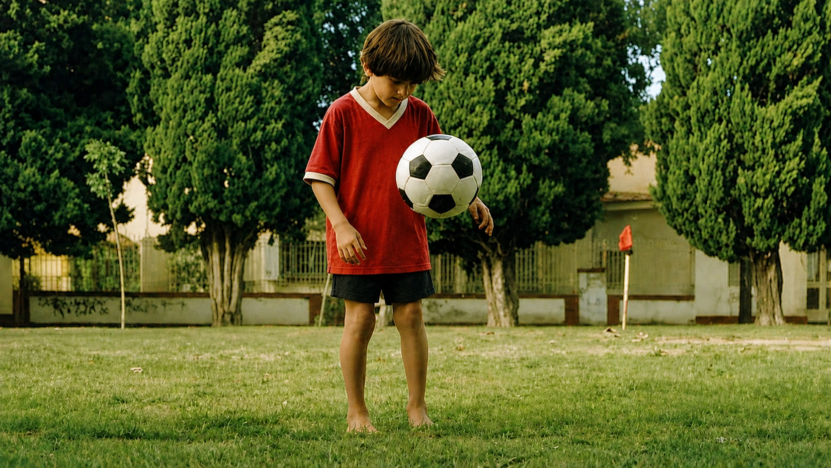 A young child in a red Newell's Old Boys kit juggling a football on a grass field — evoking the dreams of every child the foundation supports